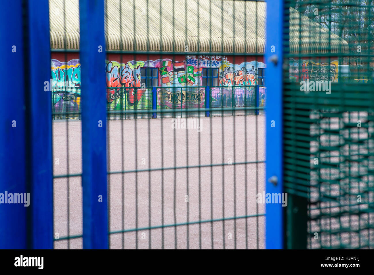 À travers une clôture métallique bleu à un painetd grafitti building Banque D'Images