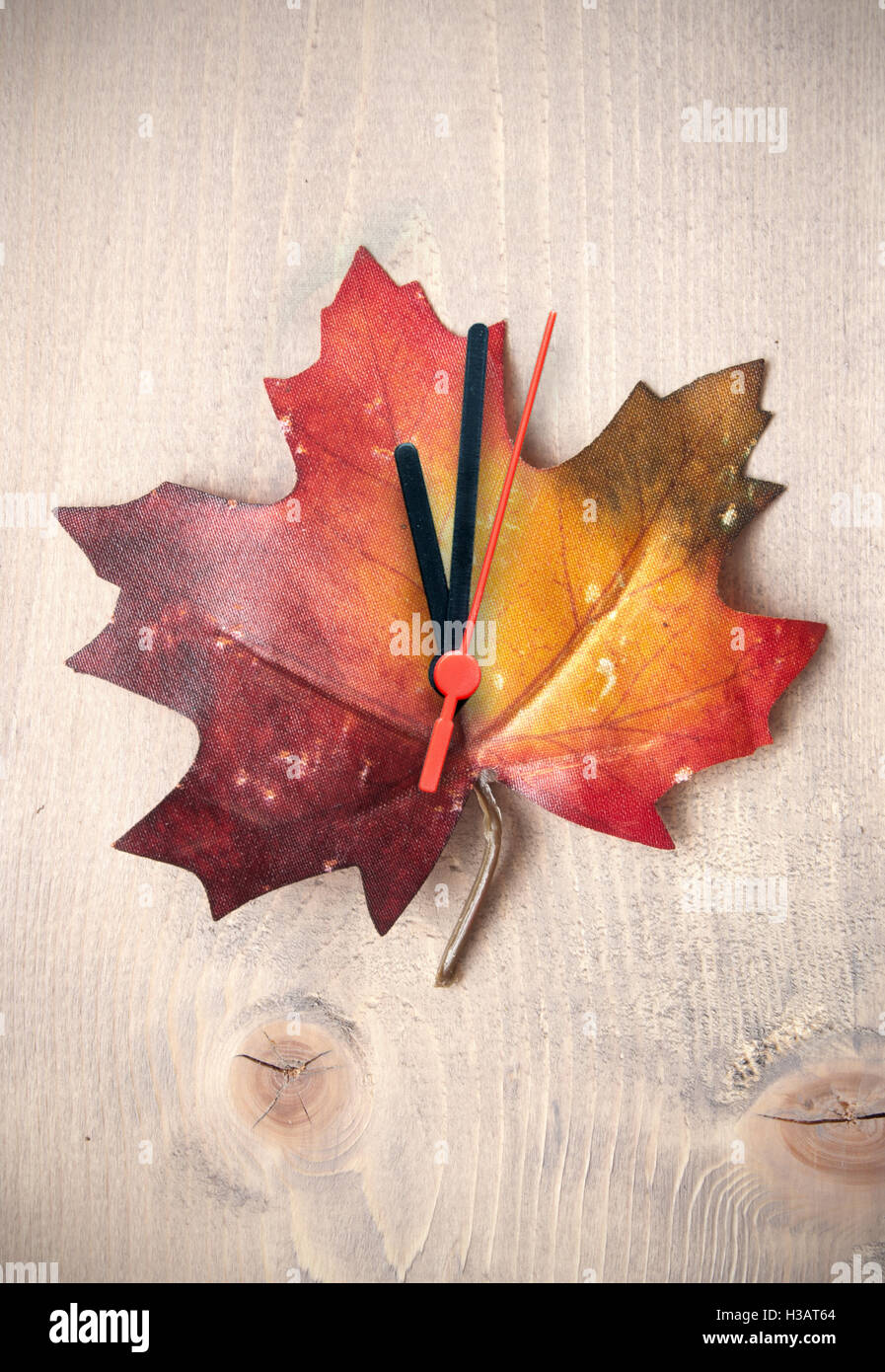 Feuille d'automne avec des aiguilles d'horloge sur le dessus d'un fond de bois Banque D'Images