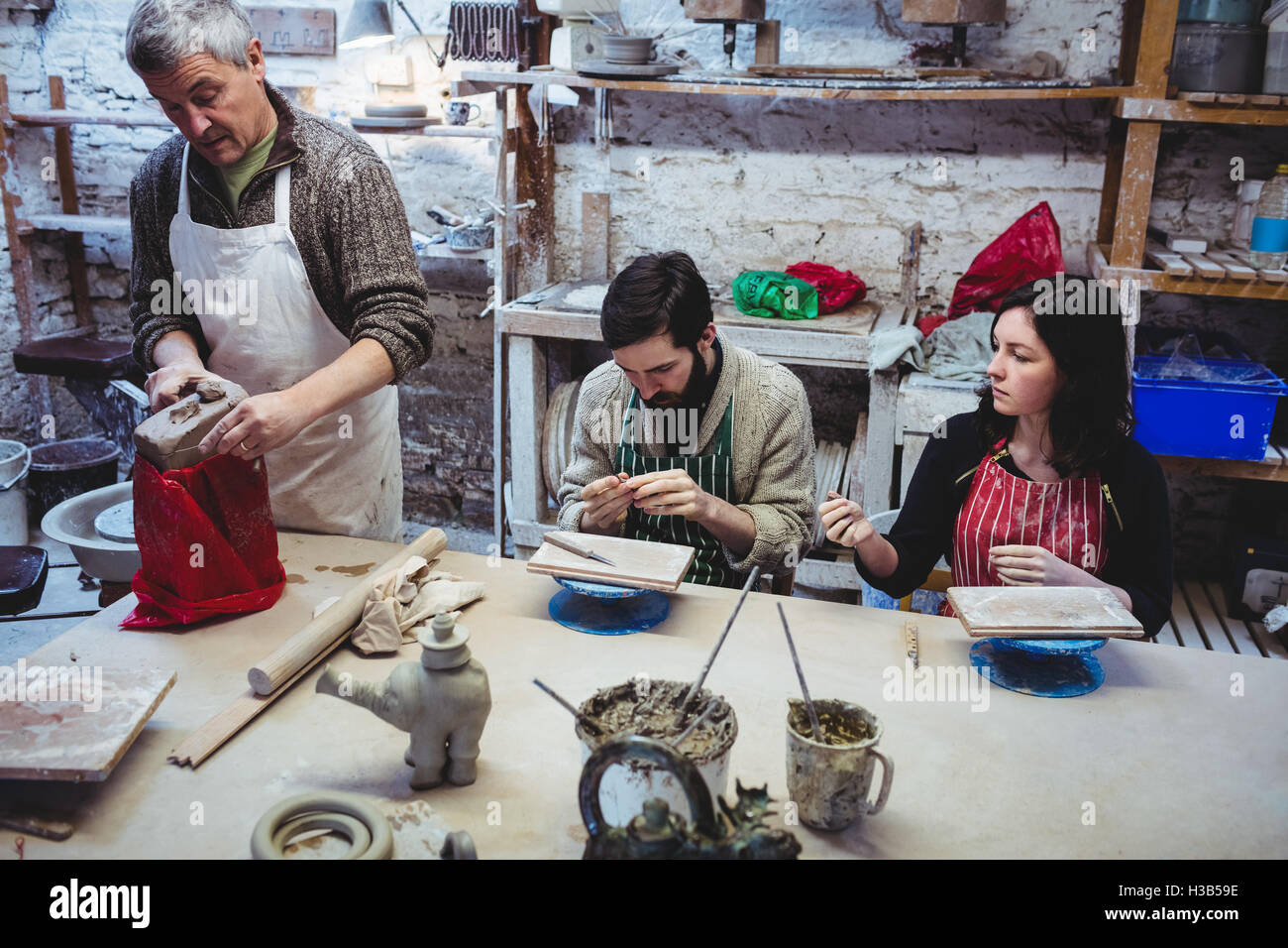 Potter mature travaillant avec des collègues à table Banque D'Images