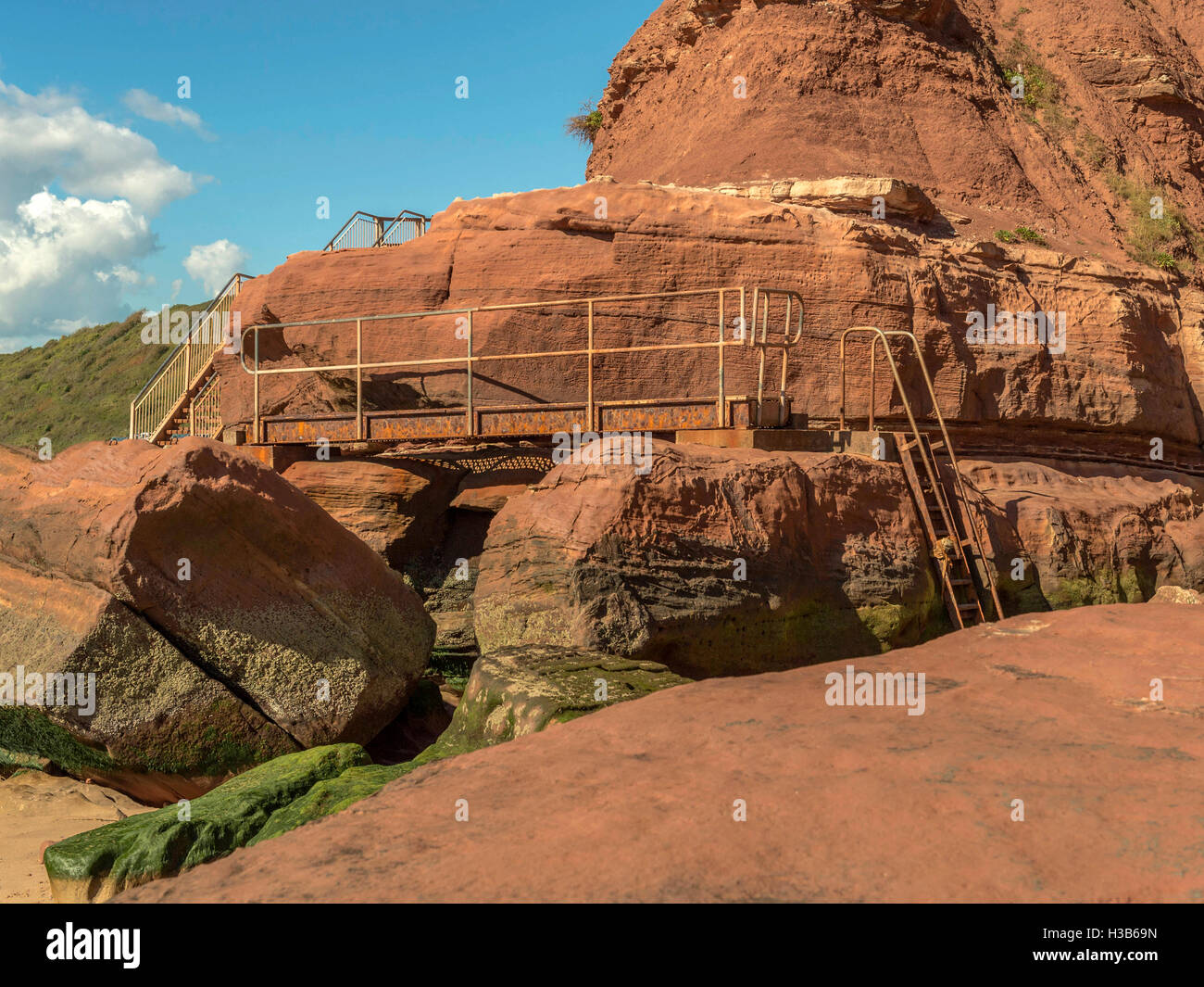 Formations rocheuses rustique visibles à marée basse et la rouille metal l'intercirculation à Orcome Point près de la ville balnéaire de Exmouth, Devon. Banque D'Images