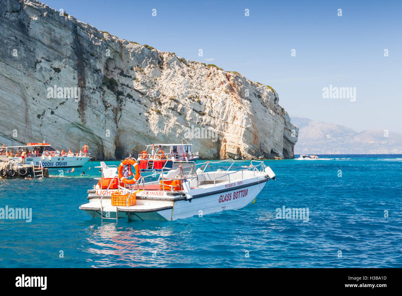 Zakynthos, Grèce - 20 août 2016 : Blanc plaisir motor bateau flottant sur l'eau de mer près de Rocky coast en journée d'été Banque D'Images