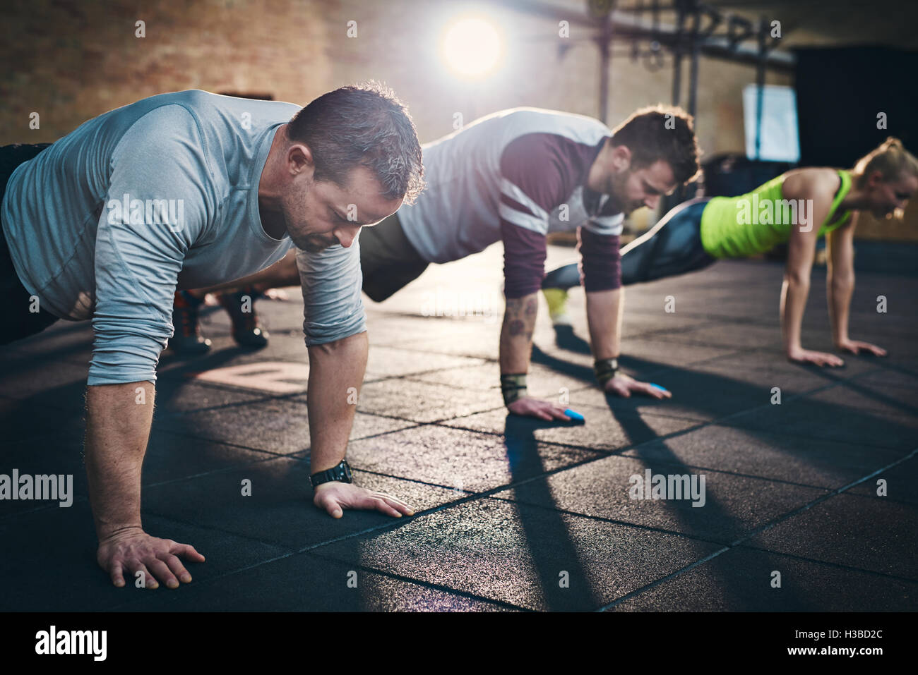 Groupe d'adultes faisant des pompes jusqu'à l'intérieur des Exercices Exercice de remise en forme physique l'entraînement en salle de conditionnement physique avec la lumière vive Banque D'Images