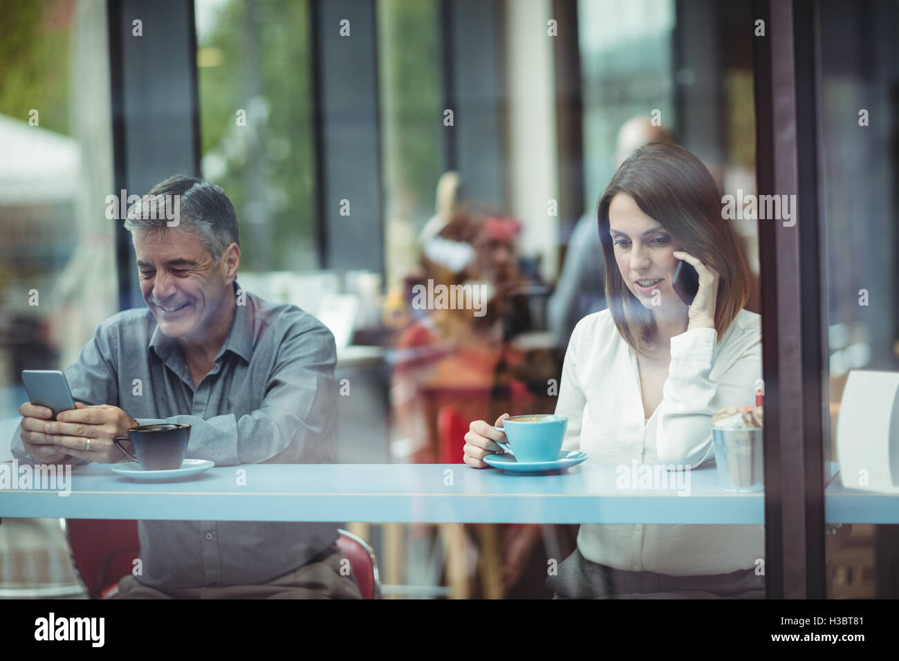 Man text messaging tandis que Woman talking on mobile phone Banque D'Images