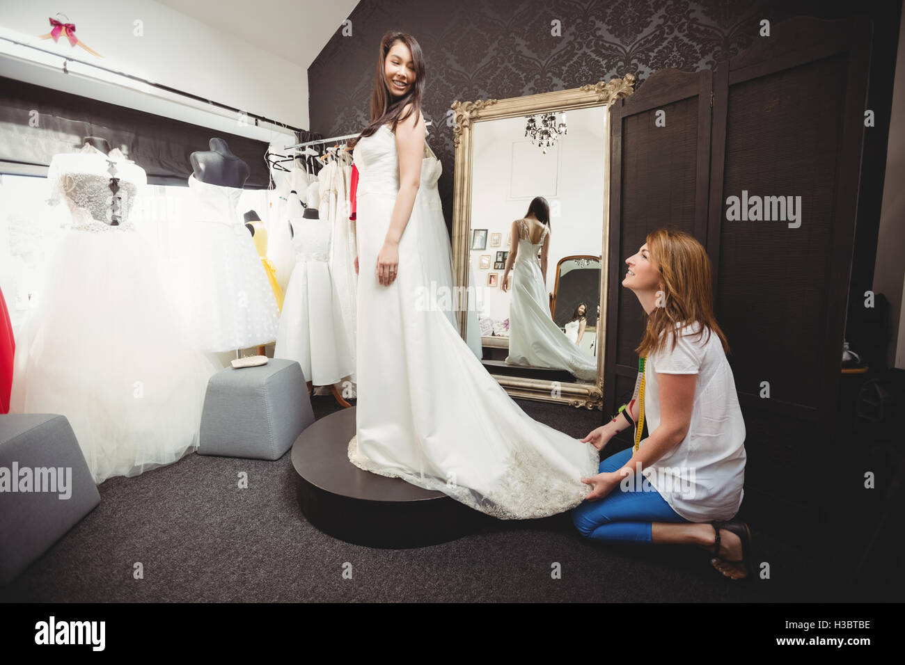 Woman trying on robe de mariage avec l'aide de creative designer Banque D'Images
