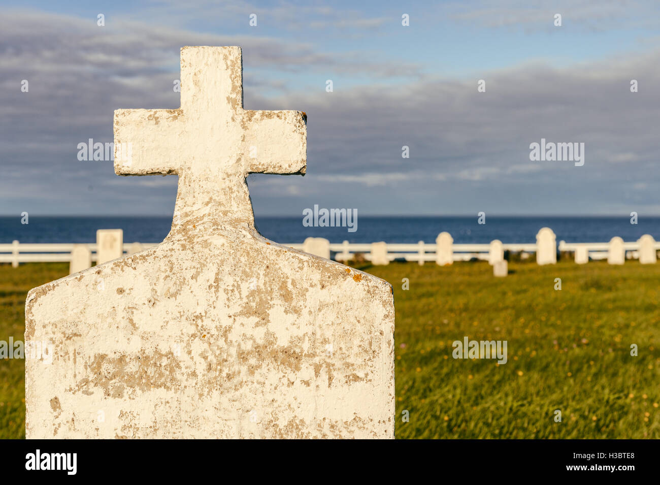 Pierre tombale dans un cimetière vide, avec en arrière-plan, de l'océan au coucher du soleil Banque D'Images