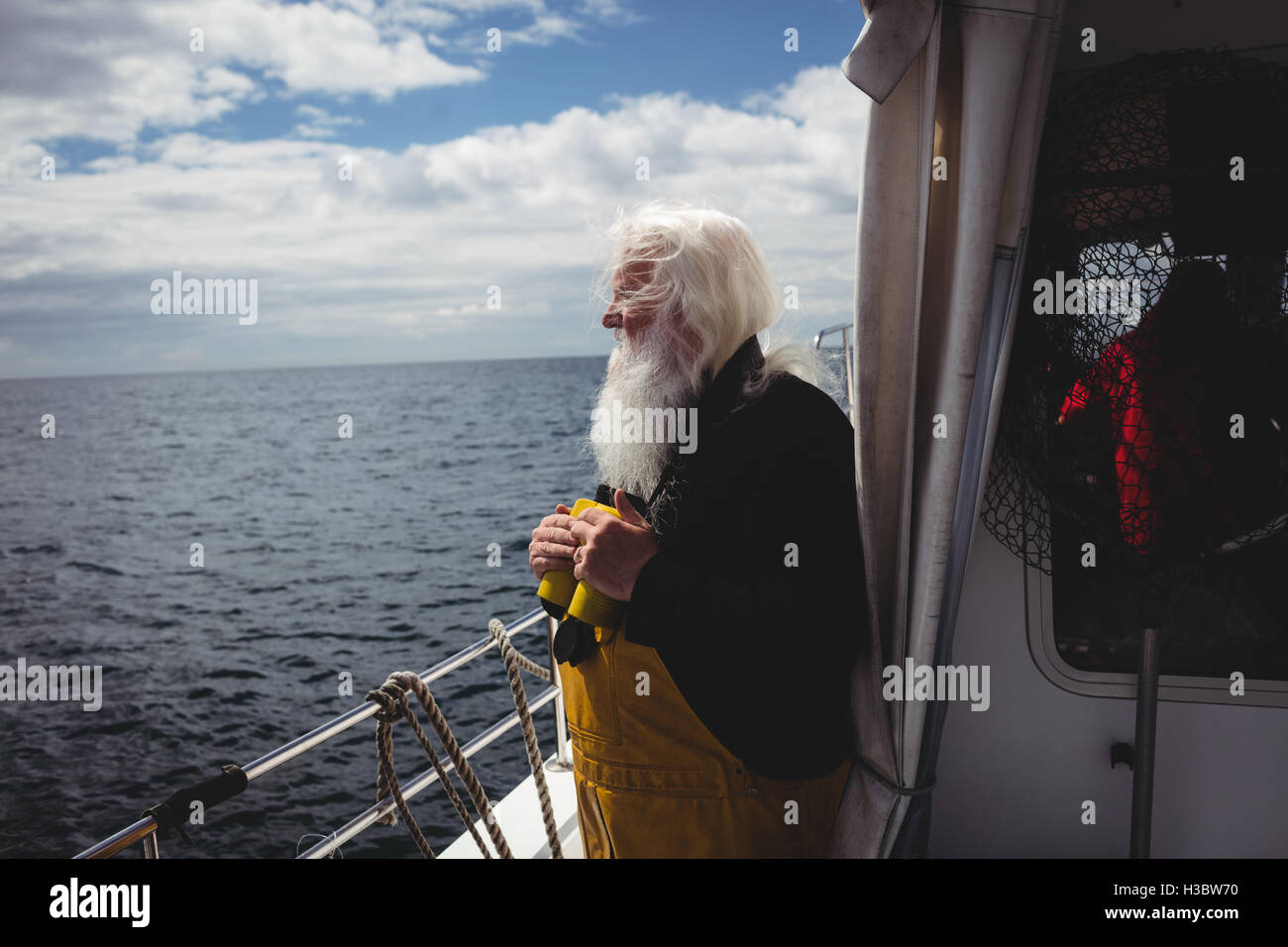 Fisherman holding binoculars et looking at view Banque D'Images
