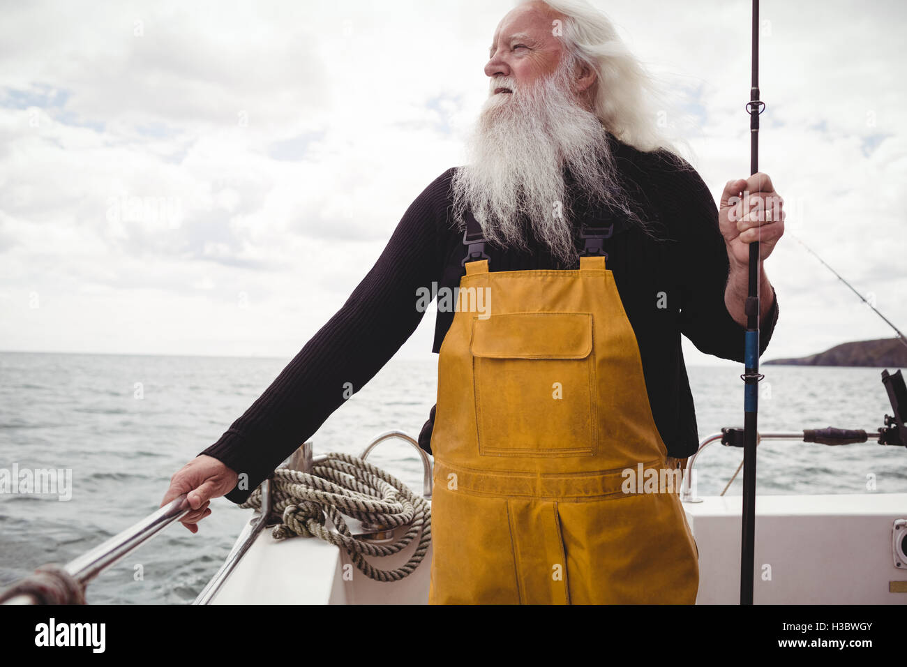 Debout sur le bateau pêcheur tenant la canne à pêche Banque D'Images