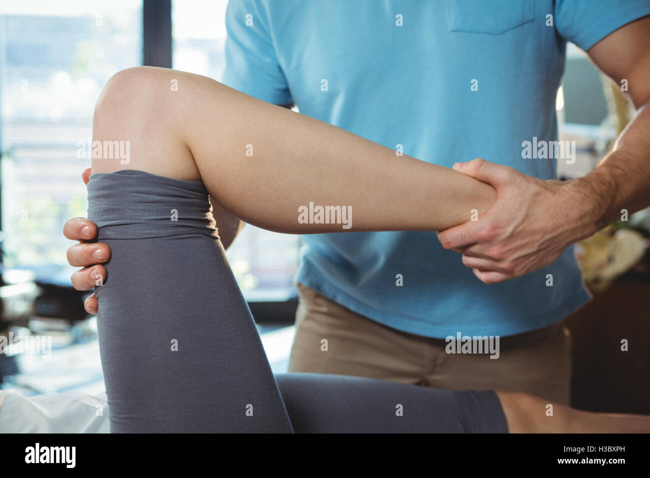 Physiothérapeute mâle à femelle massage du genou donnant patient Banque D'Images