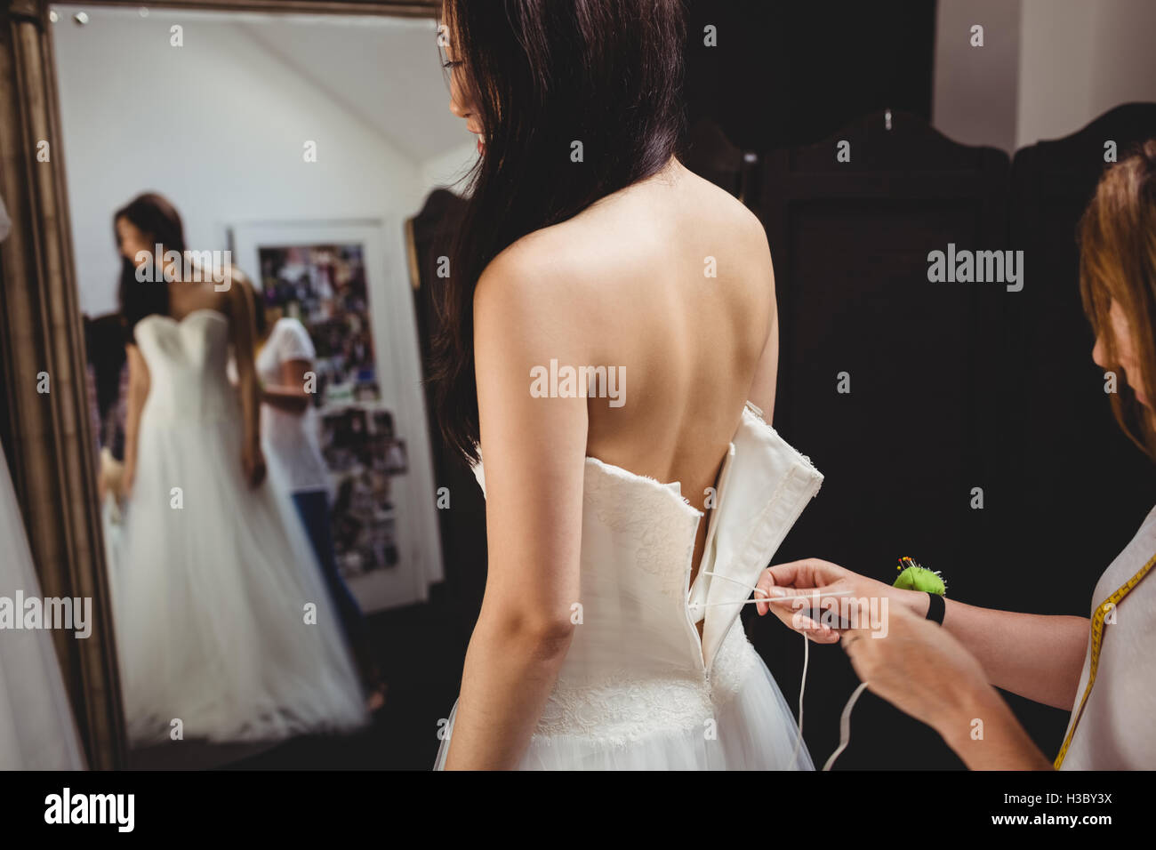 Woman trying on robe de mariage avec l'aide de creative designer Banque D'Images