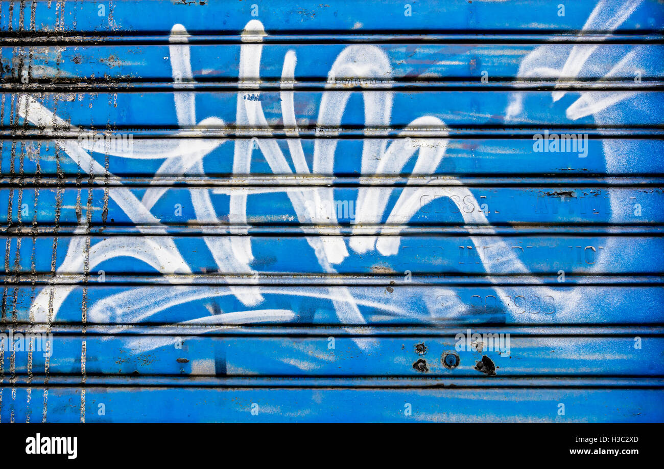Obturateur fermé couvert de graffitis et fond bleu. Banque D'Images