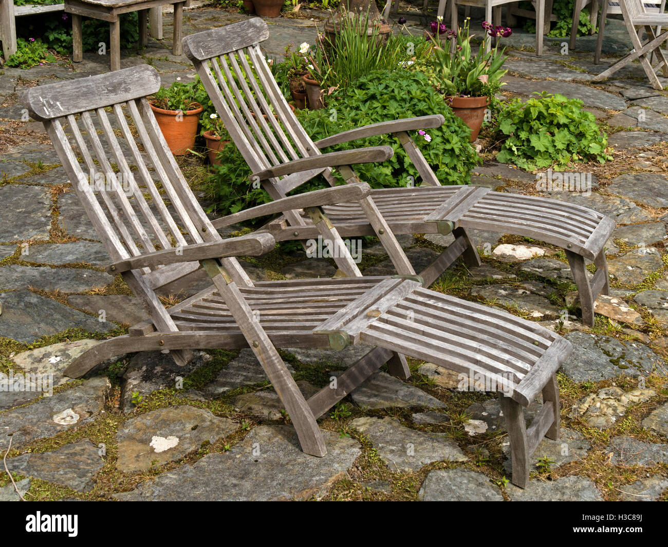 Deux vieux pont en bois chaises longues sur patio en pierre, Colonsay House Gardens, à l'île de Colonsay, Ecosse, Royaume-Uni. Banque D'Images