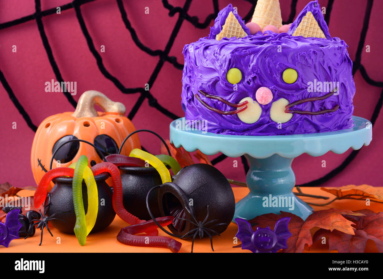 Happy Halloween cat gâteau partie nourriture avec glaçage violet et des bonbons avec des décorations de table parti annonce spider web backgroun Banque D'Images