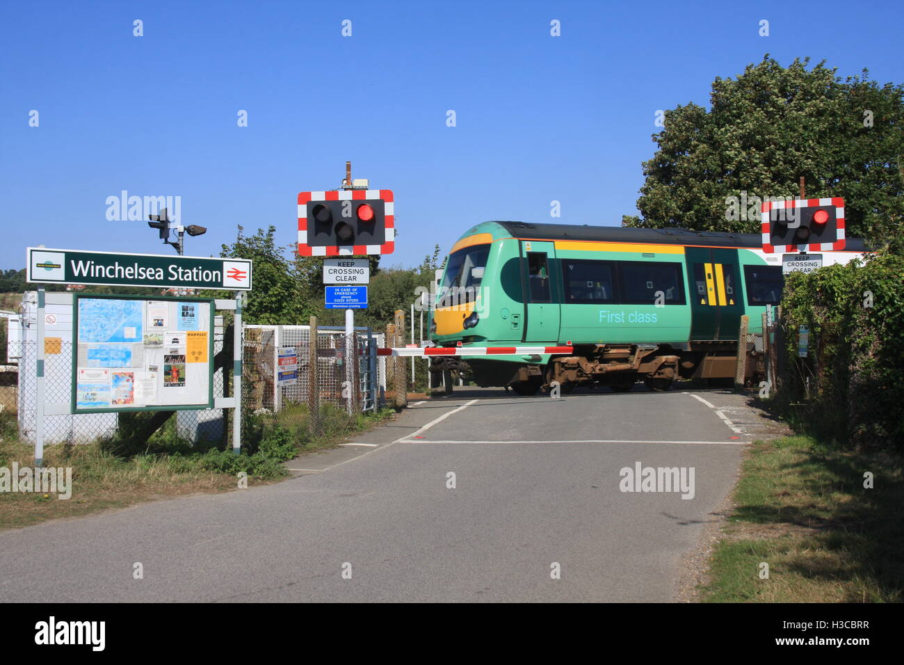 Un coup de soleil D'UN SUD DE L'UNITÉ DIESEL TRAINS SUR UN PASSAGE À NIVEAU À SUSSEX Banque D'Images