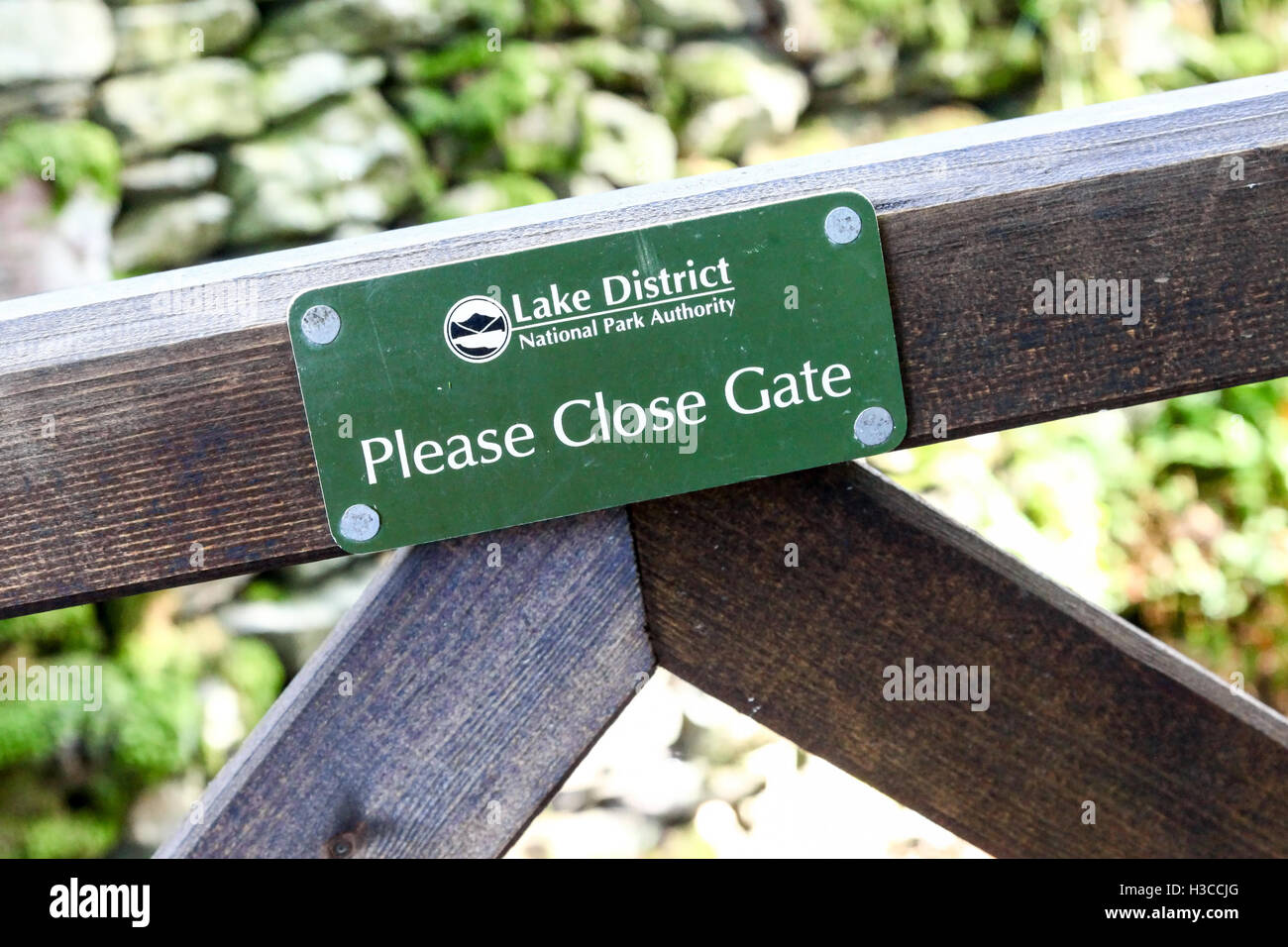 Un signe sur une barrière en bois disant Lake District National Park Authority Veuillez fermer la porte Cumbria England UK Banque D'Images