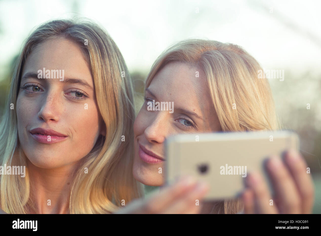 Les femmes qui posent ensemble pour selfies smartphone Banque D'Images