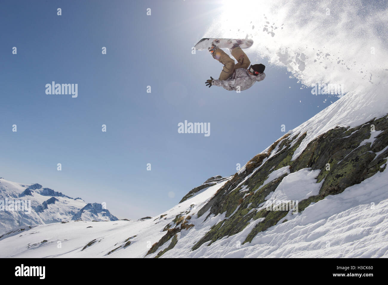 Snowboarder sautant au-dessus d'une falaise dans la station de ski Disentis 3000 Banque D'Images