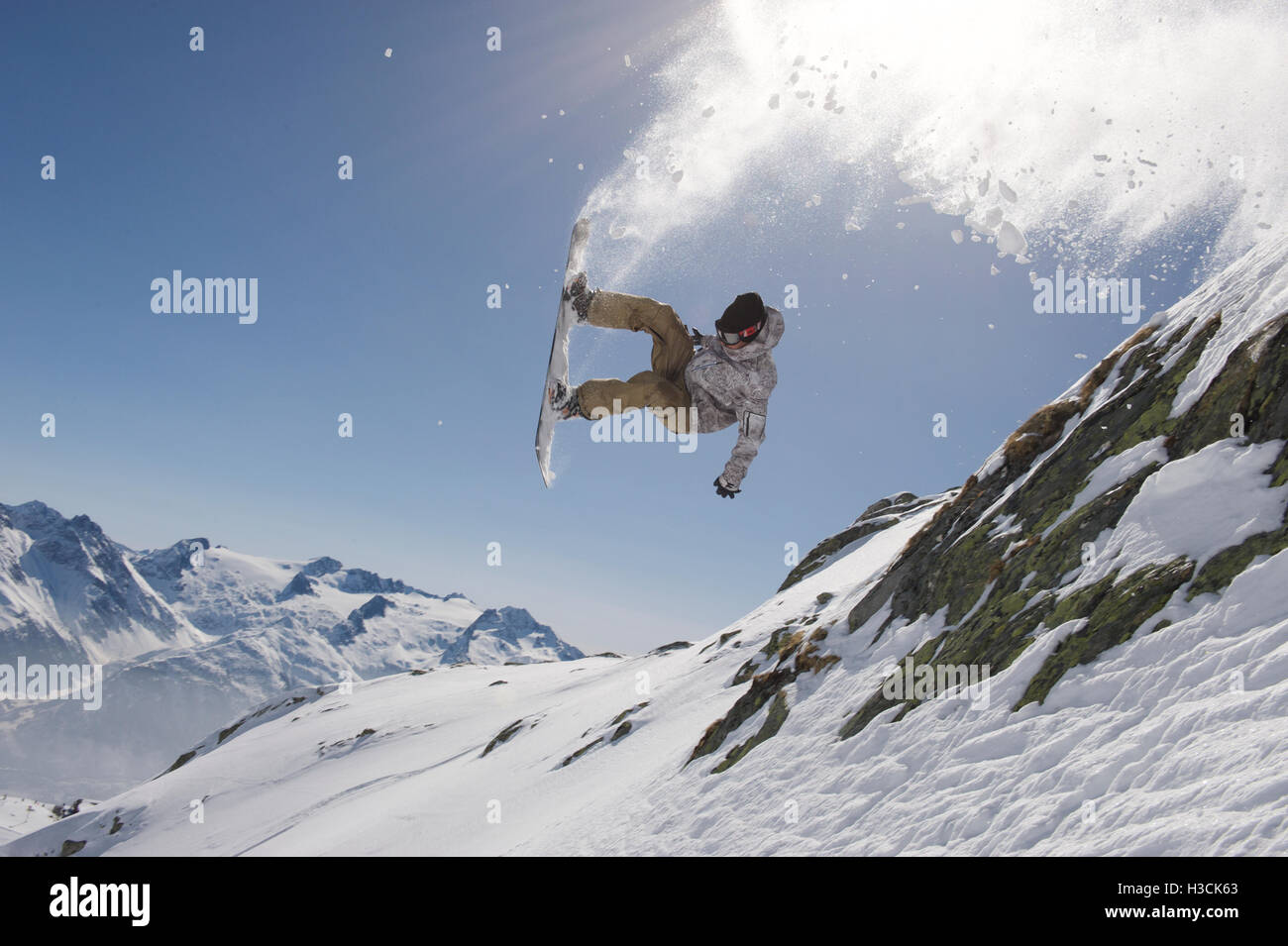 Snowboarder sautant au-dessus d'une falaise dans la station de ski Disentis 3000 Banque D'Images