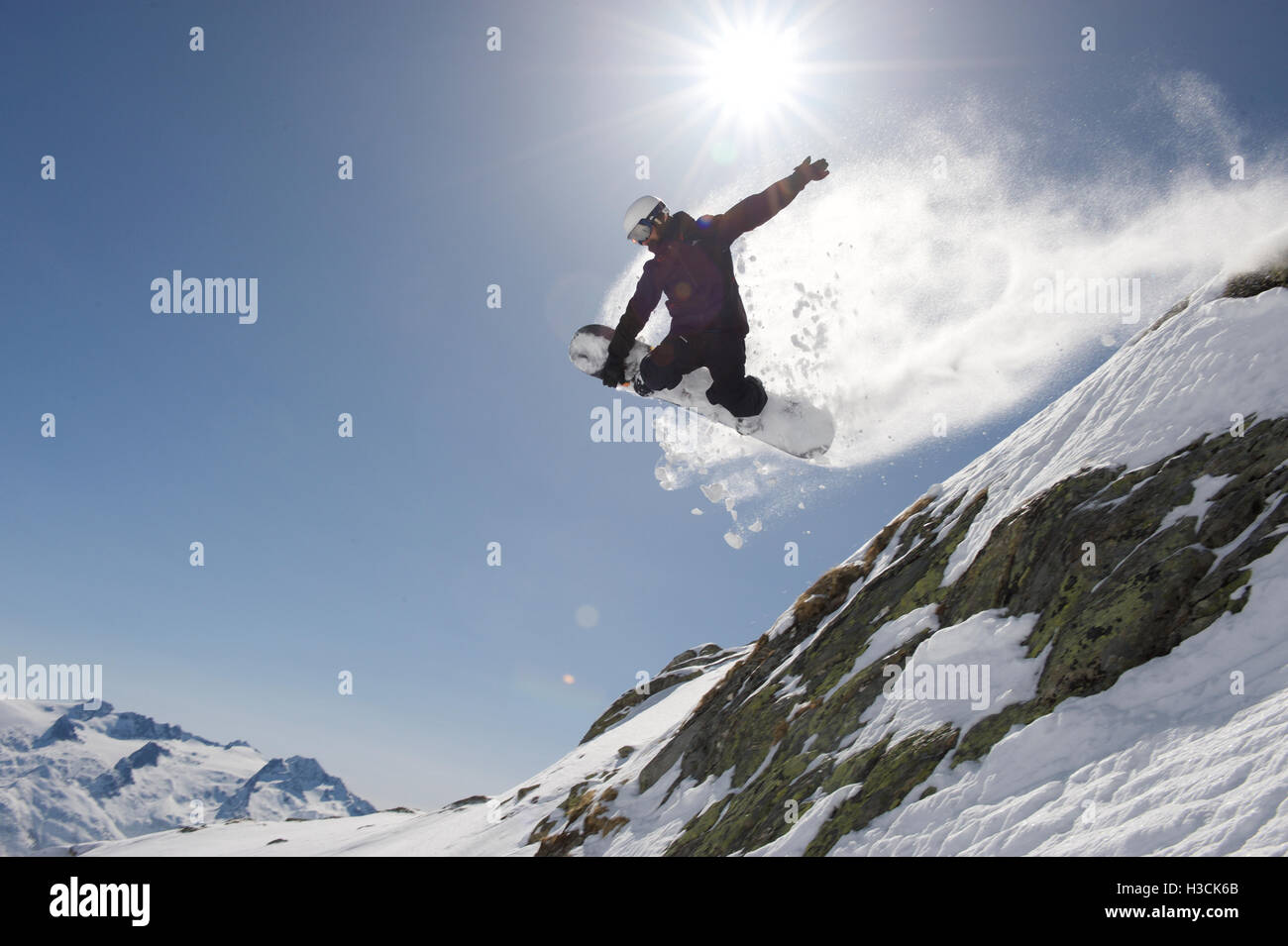 Snowboarder sautant au-dessus d'une falaise dans la station de ski Disentis 3000 Banque D'Images