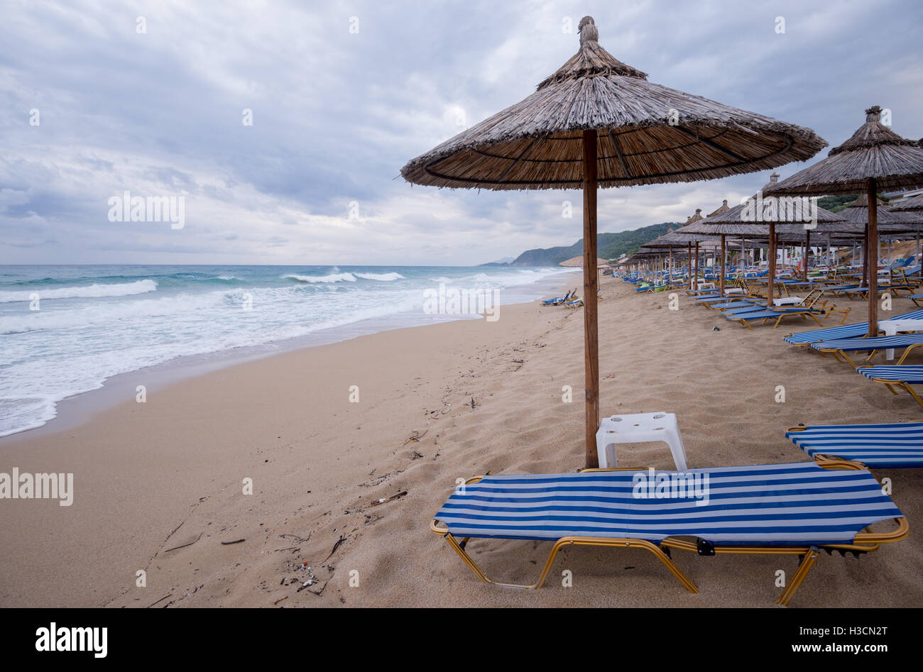 Chaume Tropical parasols sur une plage déserte dans un mauvais temps en Grèce. Banque D'Images Chaume Tropical parasols sur une plage déserte dans un mauvais temps en Grèce. Banque D'Images