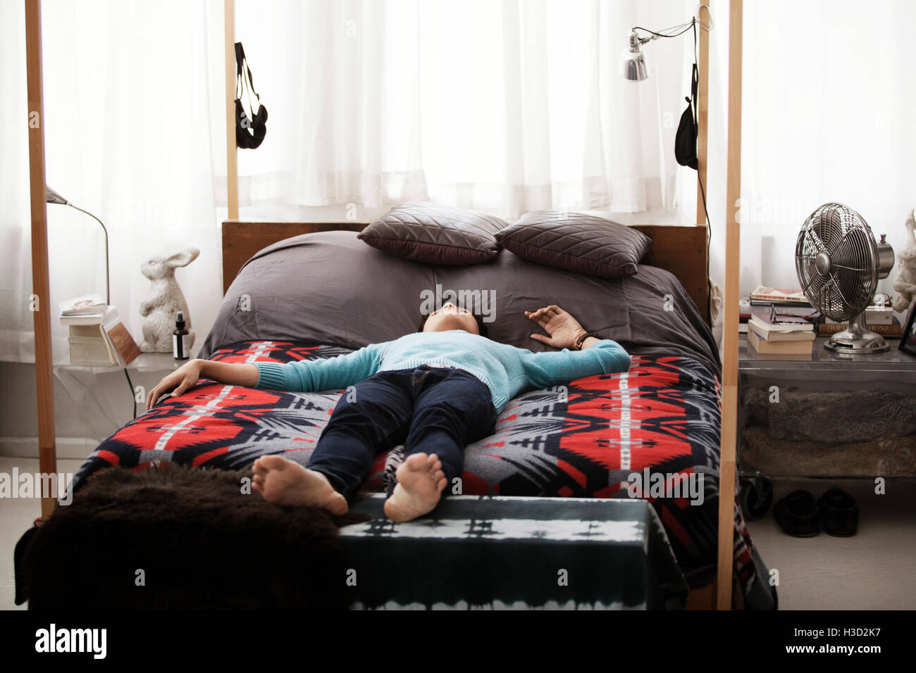Homme étendu sur un lit à baldaquin à la maison Photo Stock - Alamy