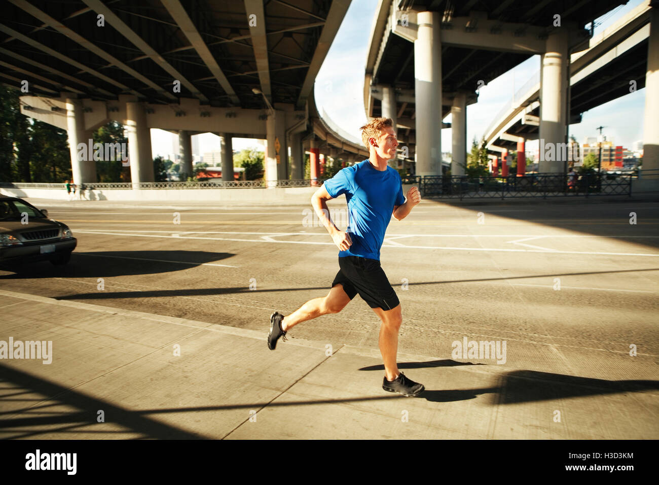 Sporty man jogging on city street sous les ponts Banque D'Images