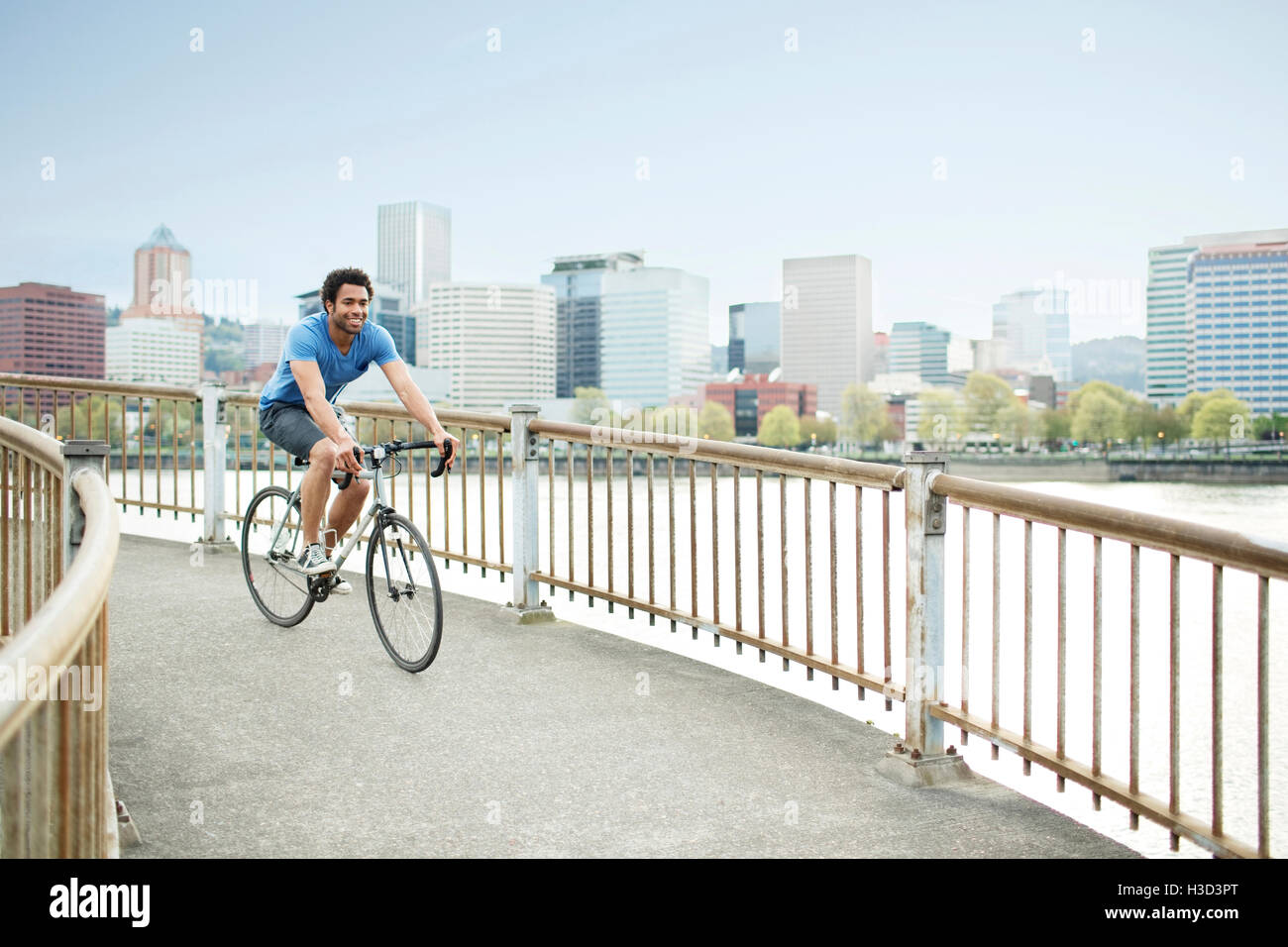Jeune homme sportif équitation location sur le pont par la rivière en ville Banque D'Images
