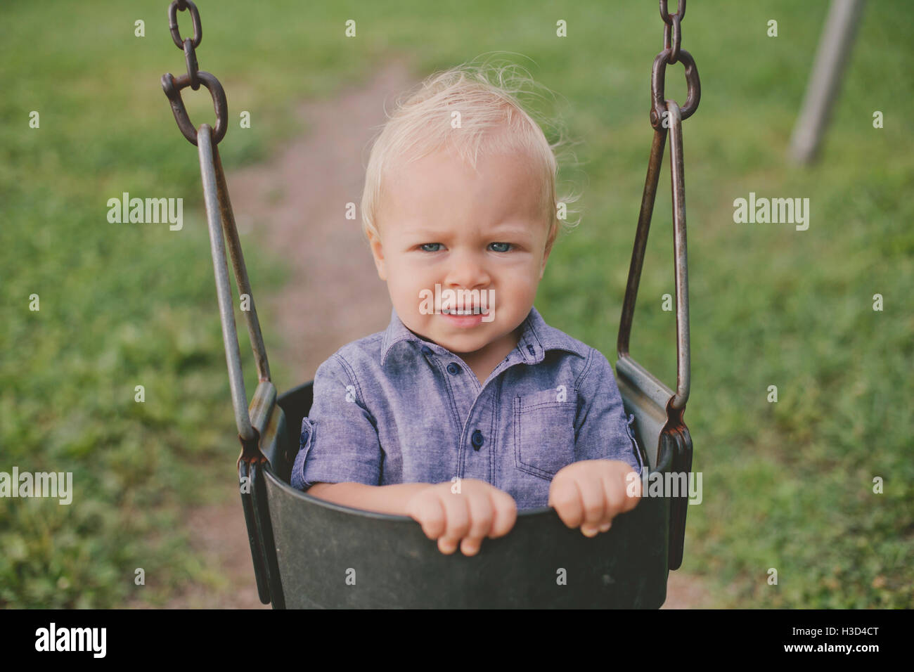 Portrait of baby boy on swing in playground Banque D'Images