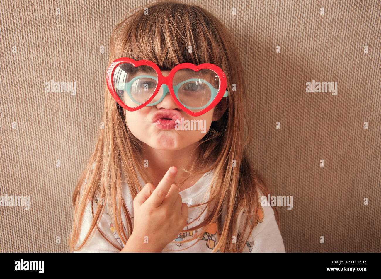 Portrait de jeune fille portant des lunettes nouveauté tout en froisser contre mur Banque D'Images
