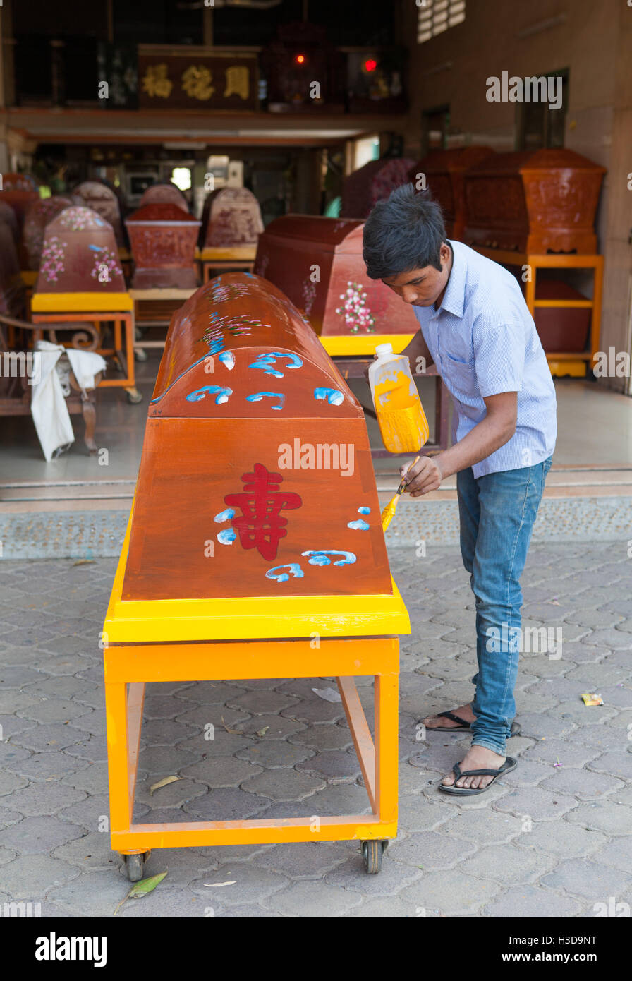 Man painting un cercueil à l'extérieur de son magasin à Phnom Penh, Cambodge. Banque D'Images
