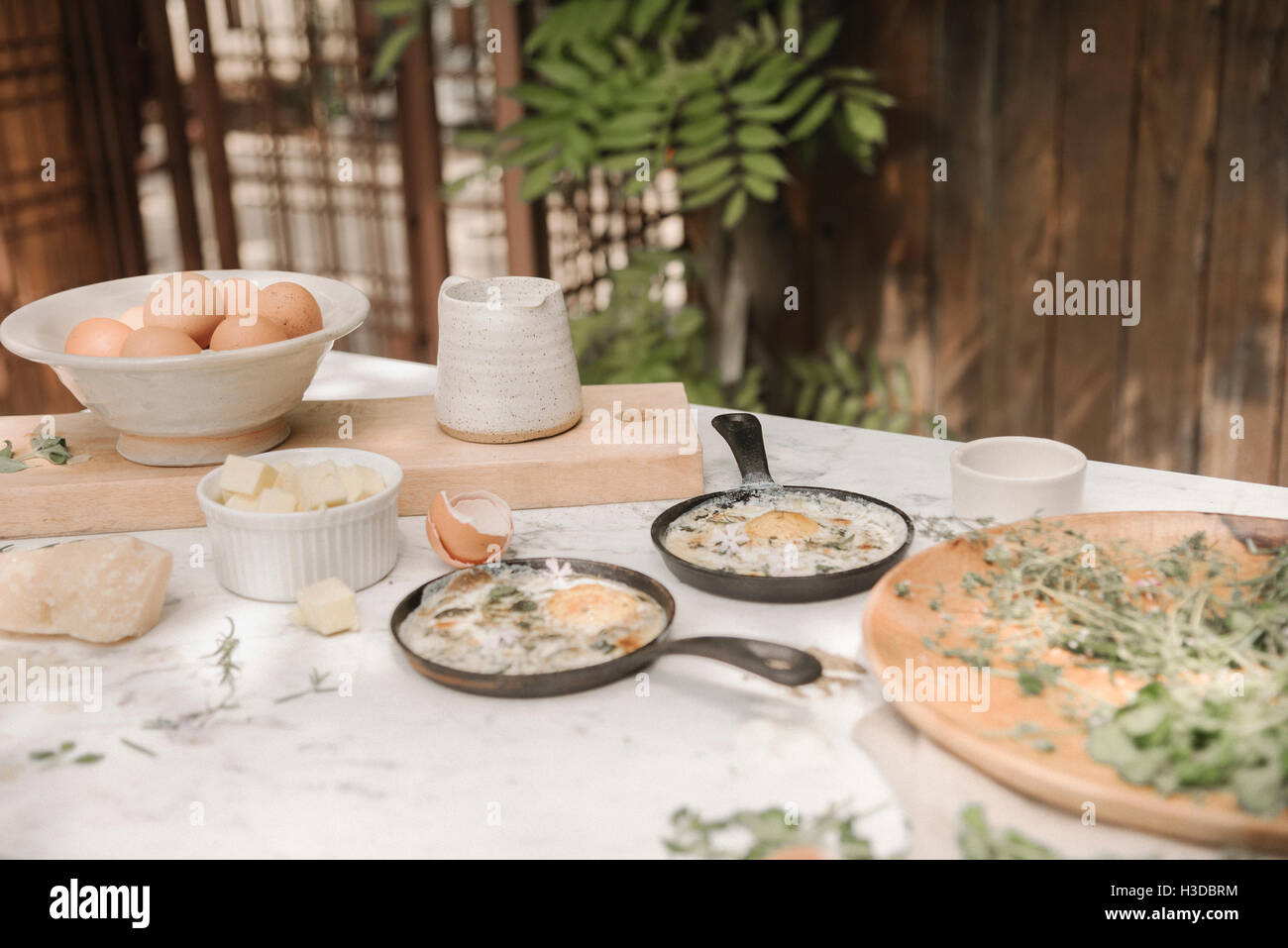 Des œufs frais dans de petites casseroles, sur une table avec des boules et un pot à lait. Banque D'Images