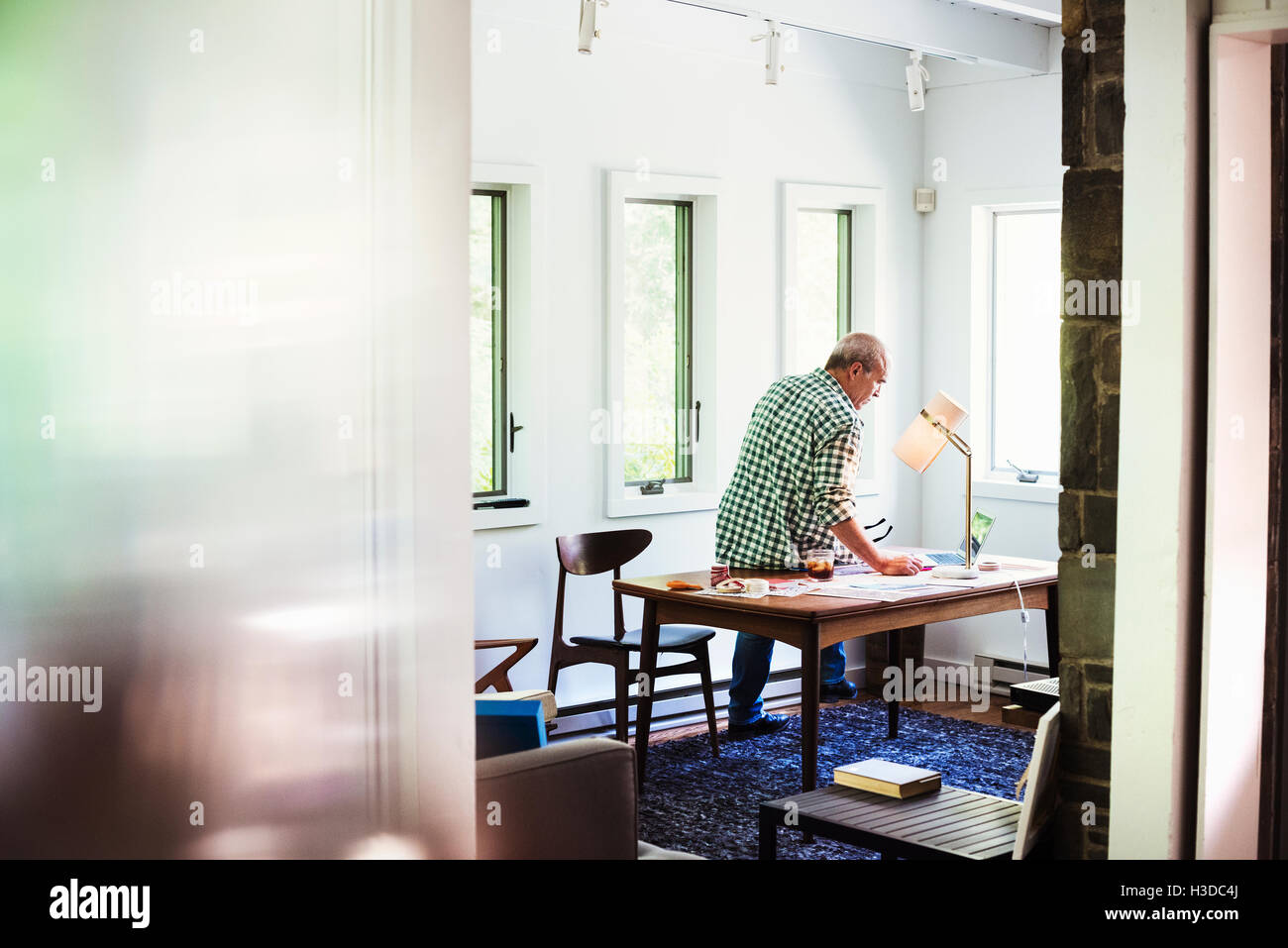 Un homme à la maison à l'aide d'un ordinateur portable sur un bureau. Banque D'Images