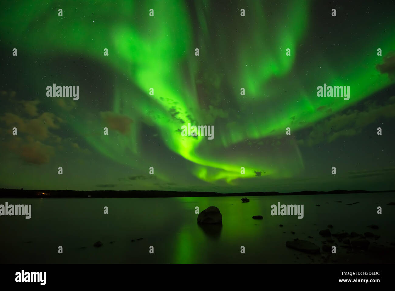 Le nord du ciel nocturne - Aurora Borealis lumineuse répand traverser le ciel étoilé au-dessus d'un lac. Banque D'Images