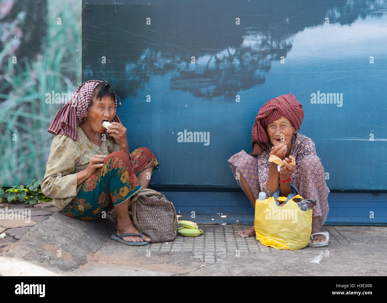 Deux vieilles femmes assises sur le trottoir à manger leur déjeuner à Phnom Penh,Cambodge. Banque D'Images