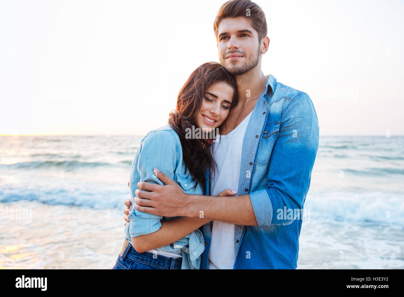 Jeune couple d'étreindre et permanent sur la plage Banque D'Images