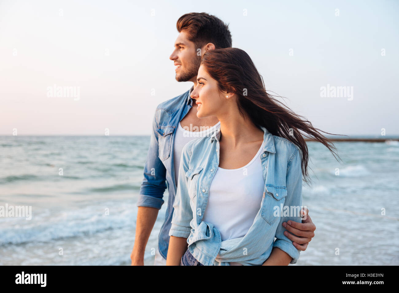 Happy young couple standing et regardant la mer sur la plage Banque D'Images