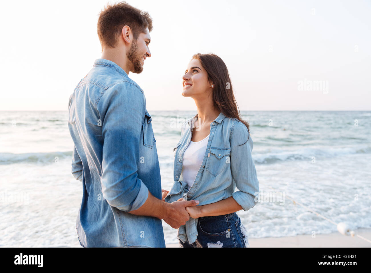Happy young couple in love debout et tenant les mains sur la plage Banque D'Images