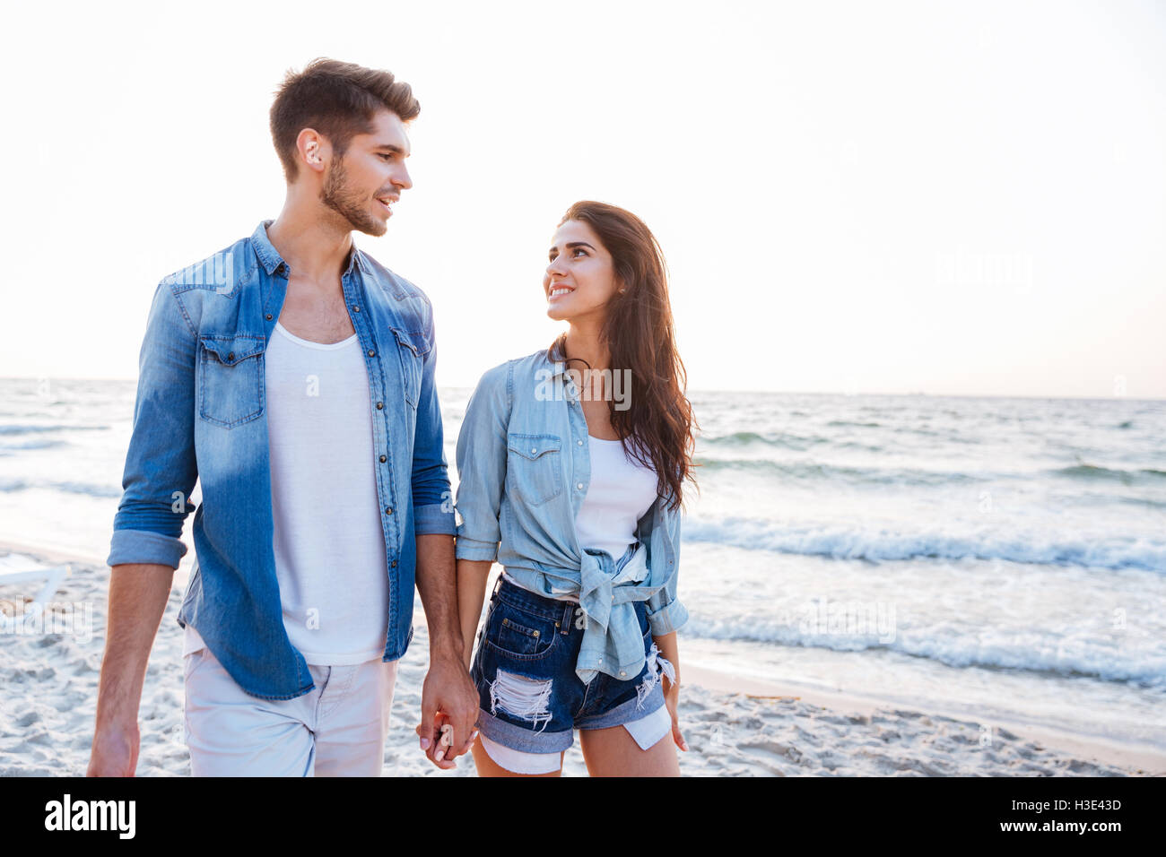 Happy young couple holding hands and walking on the beach Banque D'Images