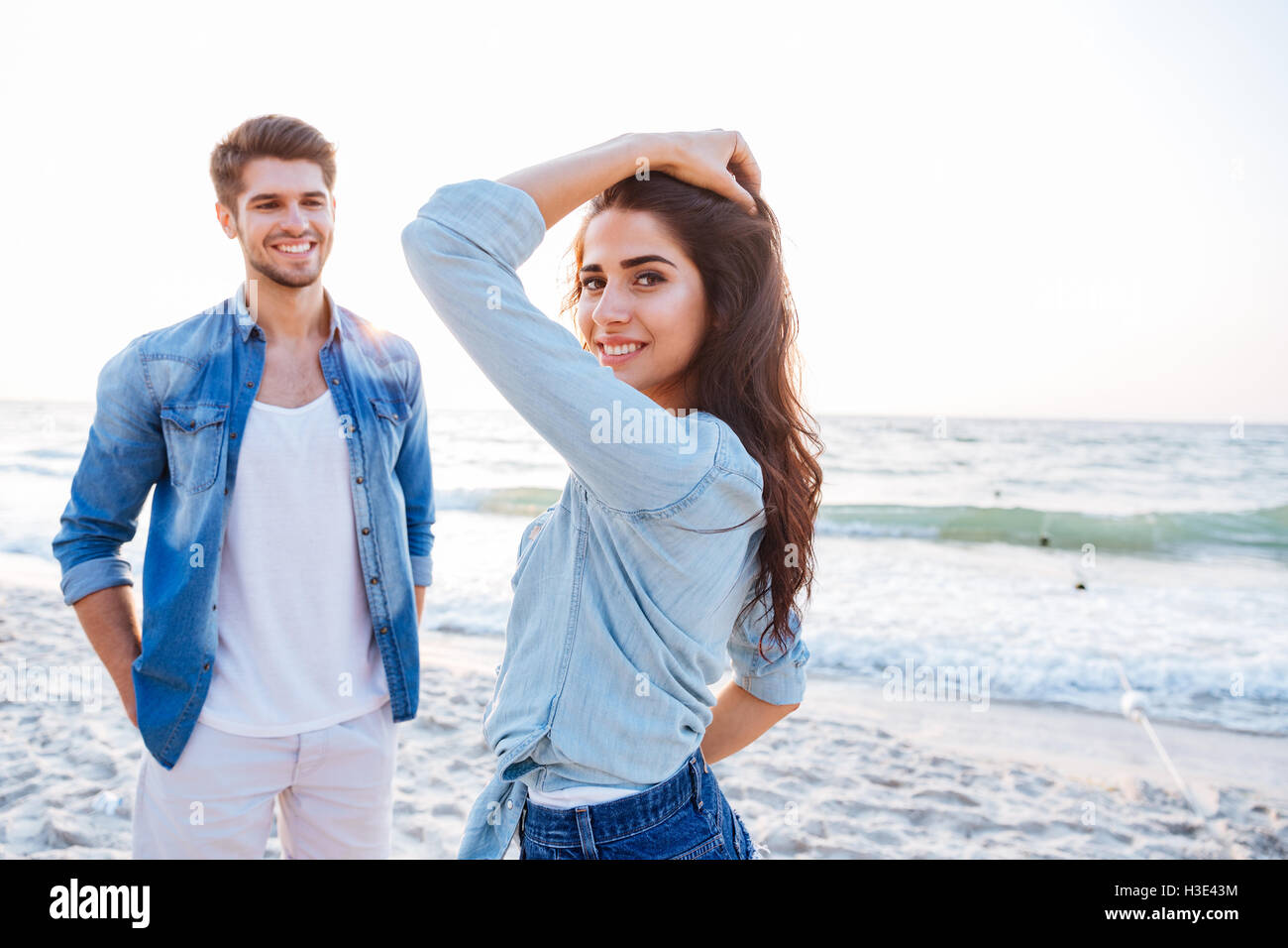 Smiling young couple standing et le flirt sur la plage Banque D'Images