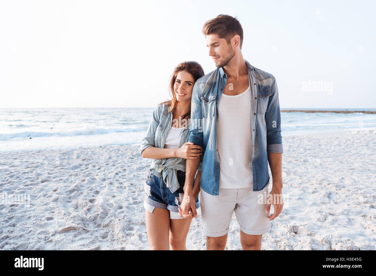 Belle jeune couple holding hands and walking at the beach Banque D'Images
