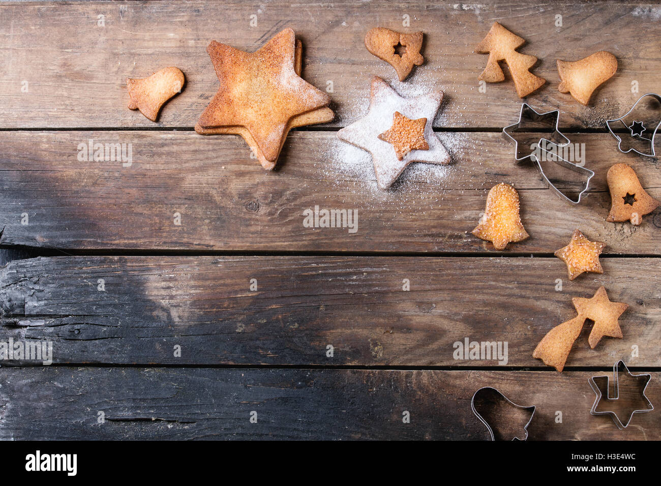 Des sablés de Noël star shape les biscuits sucrés avec du sucre en poudre de taille différente et d'un emporte-pièce sur la surface en bois ancien Banque D'Images