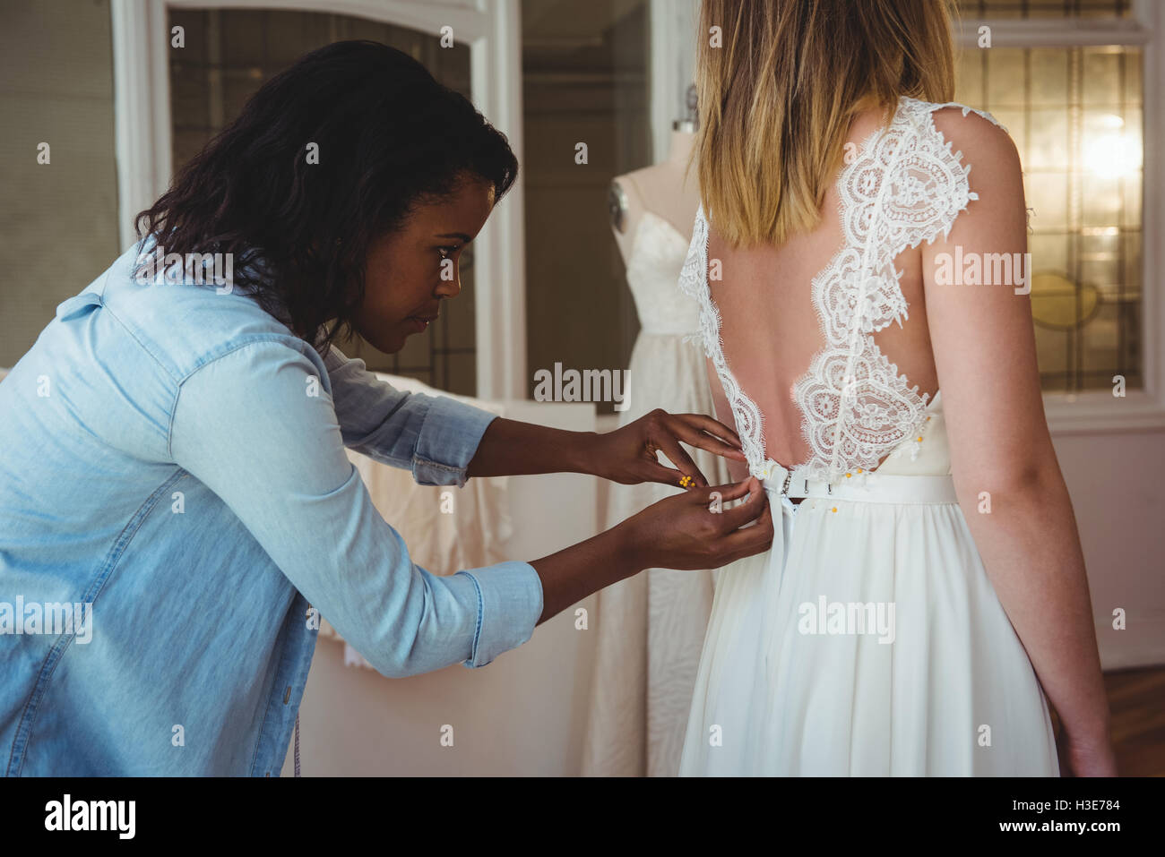 Woman trying on robe de mariage avec l'aide de designer de mode Banque D'Images