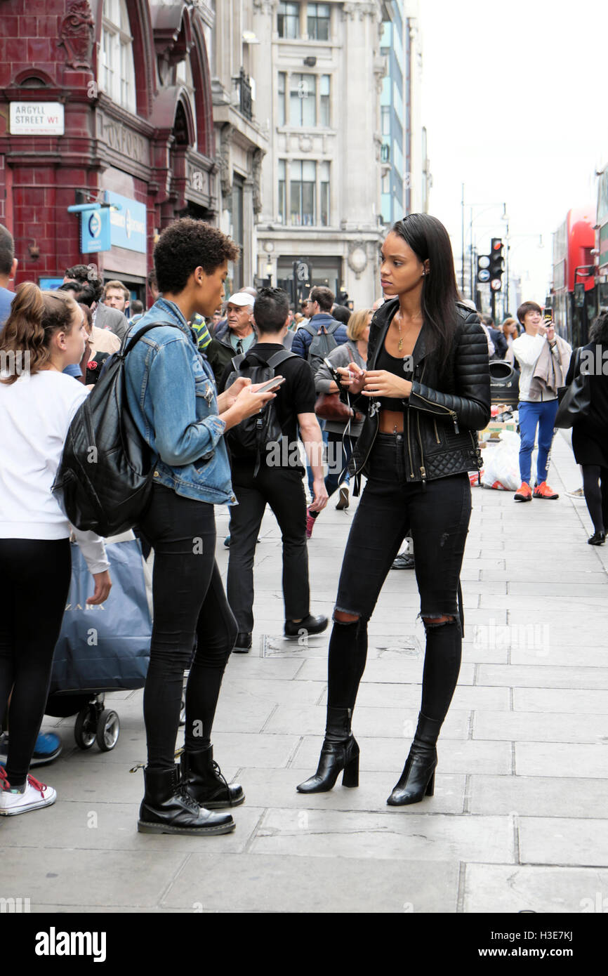 Les jeunes femmes à la mode britannique dans la conversation alors que les gens à pied d'Oxford Street en scène près d'Oxford Circus à Londres W1 England UK KATHY DEWITT Banque D'Images