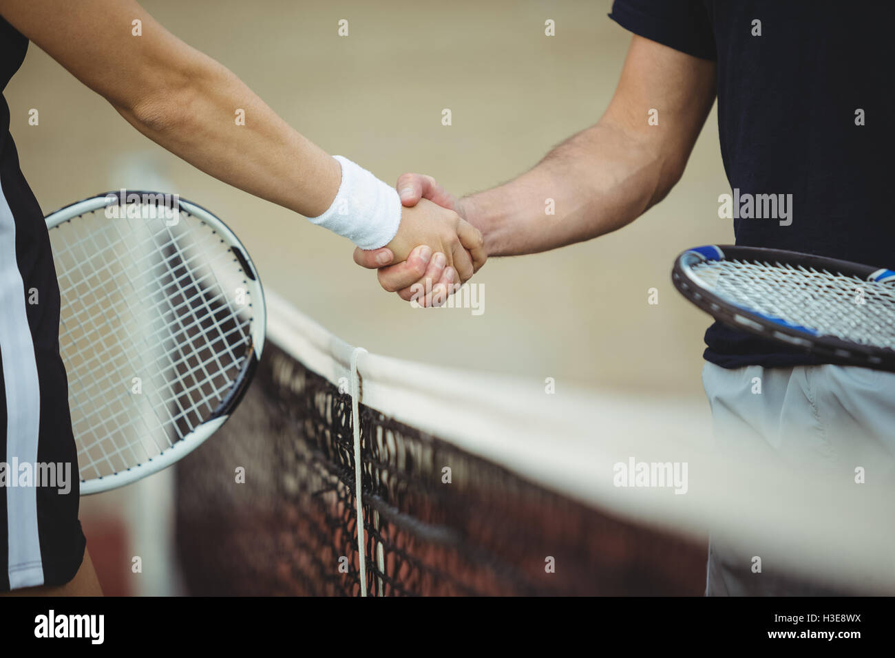Mid section de joueurs de tennis se serrer la main dans la cour Banque D'Images
