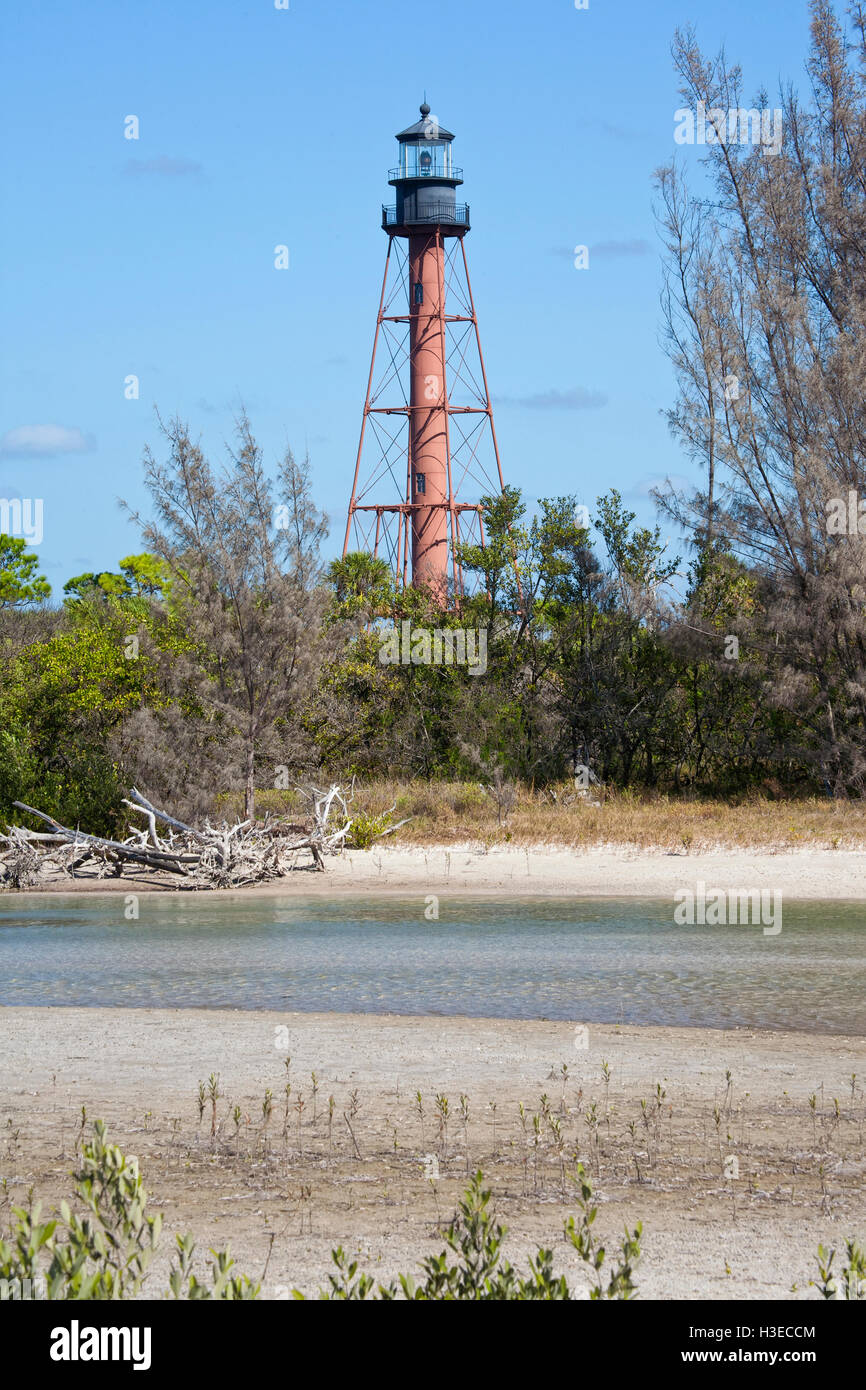 La tour de squelettique brun Anclote Key Lighthouse position contre un ciel bleu avec un ruisseau qui traverse l'eau. Banque D'Images