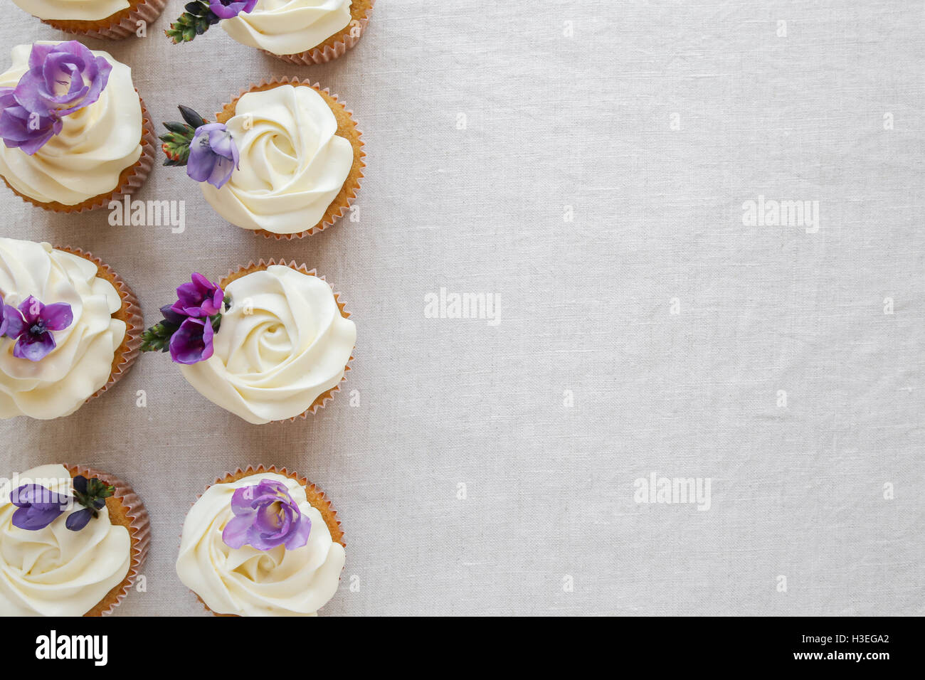 Fleur de vanille cupcakes avec glaçage violet fleurs comestibles, copy space background Banque D'Images