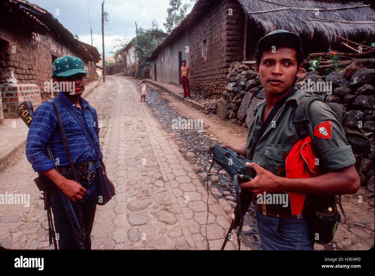 TENANCINGO, EL SALVADOR, mars 1984 : - dans le FPL Les zones de contrôle. Deux guérilleros font leur chemin à travers les rues abandonnées de cette ville disputée. Banque D'Images
