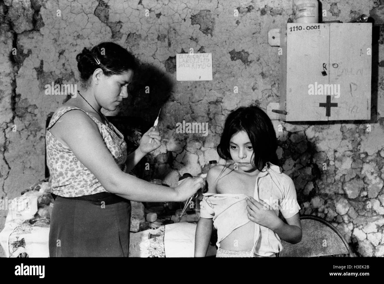 EL SALVADOR, GUAZAPA, mars 1984 : Un paramédic formé d'un enfant donne une inoculation. Banque D'Images