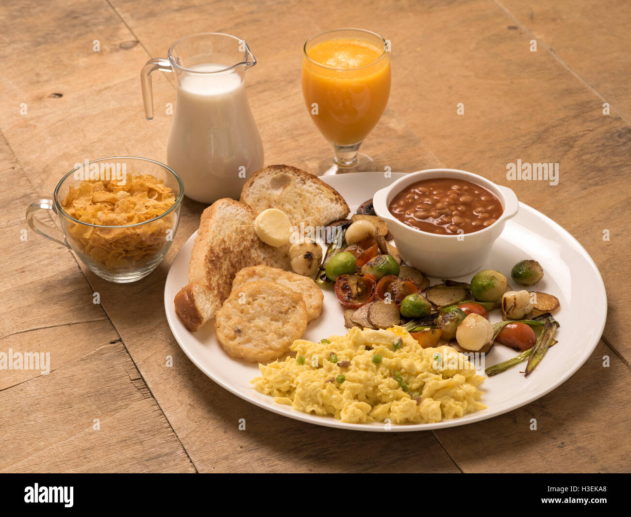 Petit déjeuner continental - oeuf brouillé, haricots cuits au four, pain grillé, avoine, lait, tomates frites avec du jus Banque D'Images