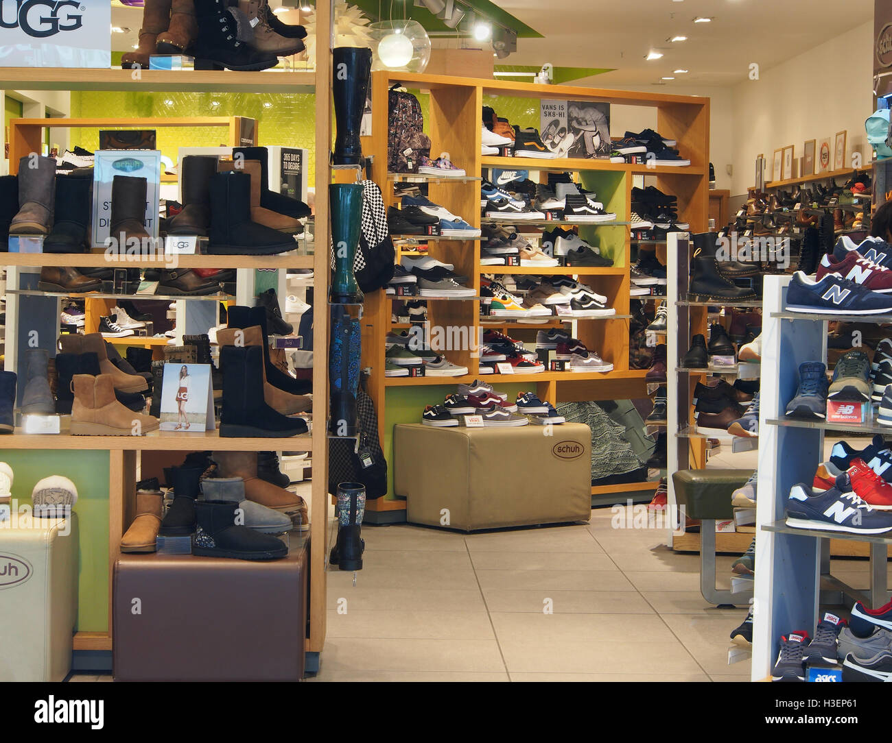 Intérieur de Shuh magasin de chaussures dans le centre de Manchester, Angleterre, RU, montrant les chaussures, formateurs et Wellington sur l'affichage sur les étagères. Banque D'Images