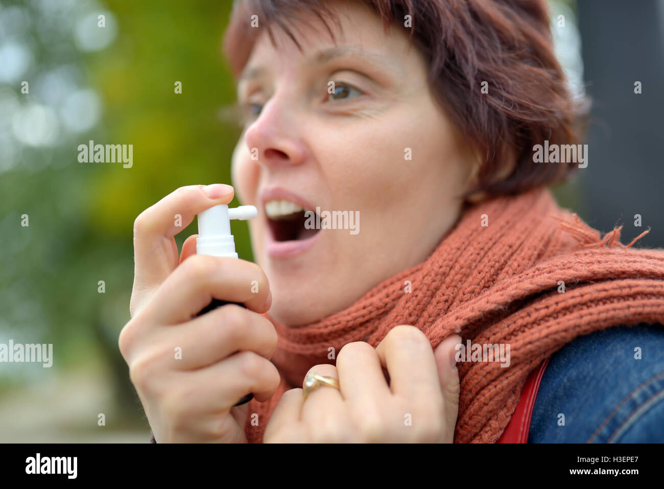 Jeune femme à l'aide de pulvérisation de la gorge dans la saison froide Banque D'Images